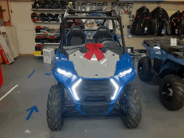 a blue and silver polaris atv with a red bow