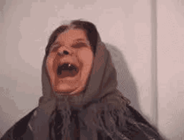 a woman wearing a scarf is making a funny face with her mouth open .