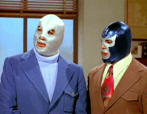 two men wearing masks and suits are standing next to each other