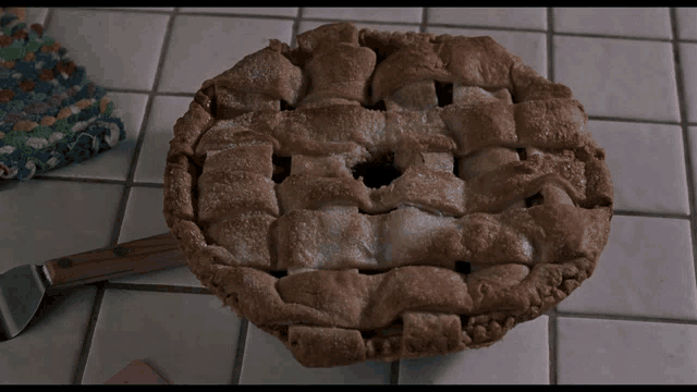 a pie with a hole in the middle is on a counter next to a knife