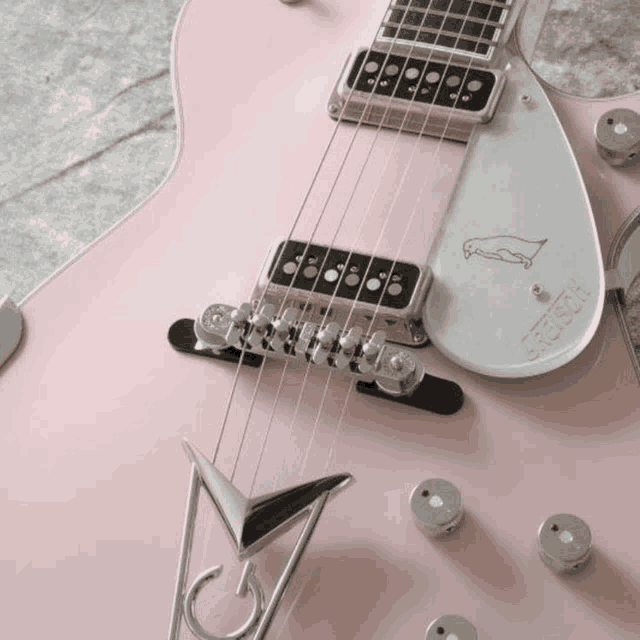 a close up of a pink electric guitar with the word gretsch on the back