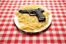 a plate of spaghetti and a gun on a red and white checkered table cloth .