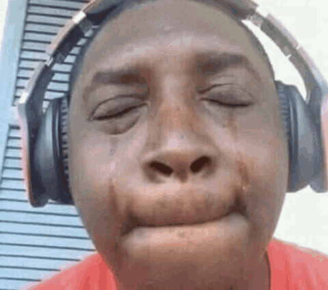 a man wearing headphones is crying with his eyes closed and tears running down his face .