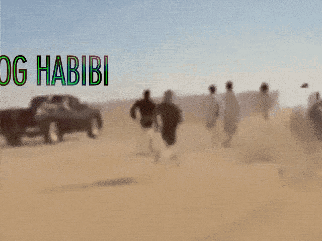 a blurry picture of people walking in the desert with og habibi written on the bottom