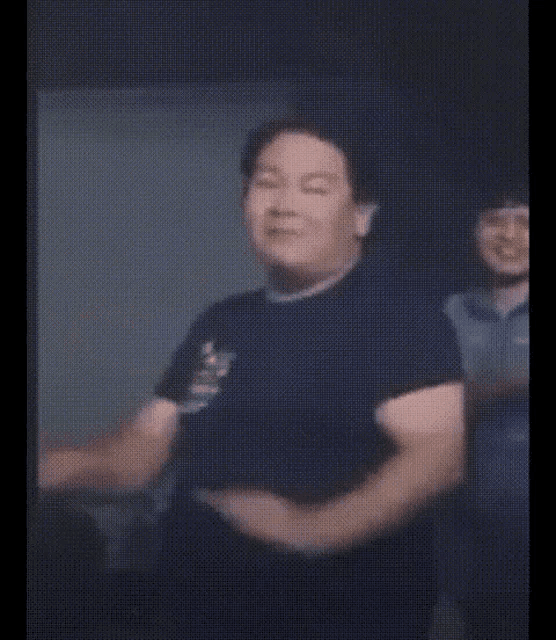 a man in a black t-shirt is dancing in a room .