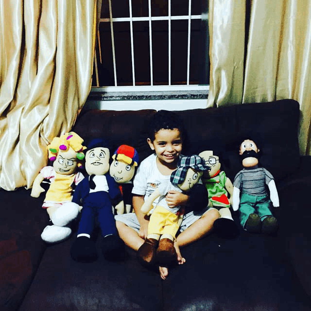 a young boy sits on a couch surrounded by stuffed toys