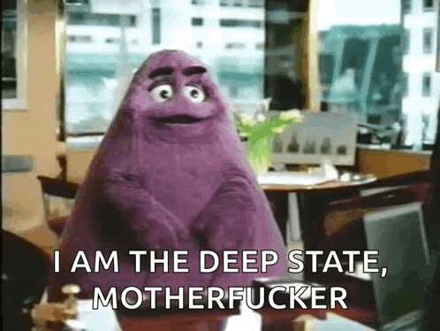 a purple puppet is sitting at a desk and says i am the deep state motherfucker