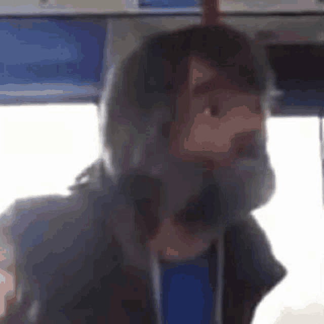 a man with a beard is sitting on a bus with his mouth open .