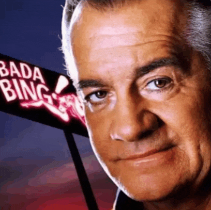 a close up of a man 's face in front of a sign that says " bada bing "