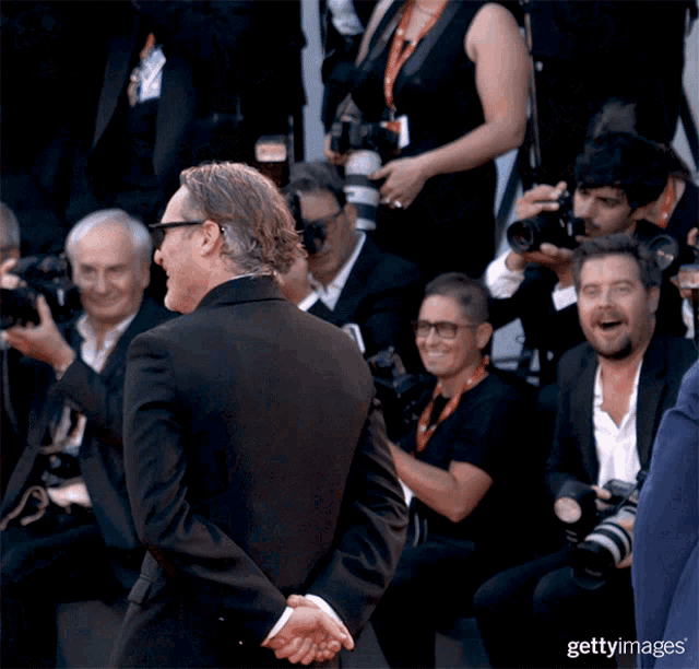 a man in a black suit stands in front of a crowd of people holding cameras with the word getty images on the bottom