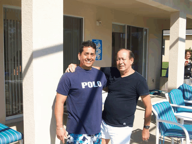 a man wearing a polo shirt stands with another man