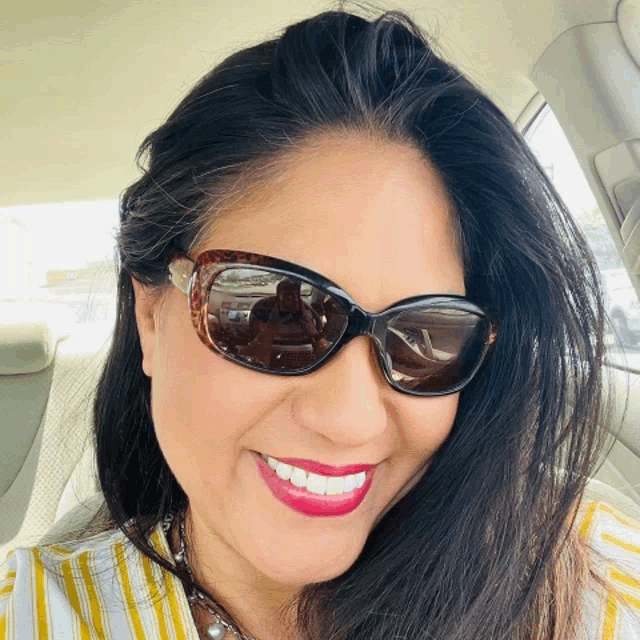 a woman wearing sunglasses and red lipstick is smiling