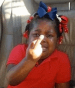 a little girl with a bow in her hair is sitting in a car and giving the middle finger .