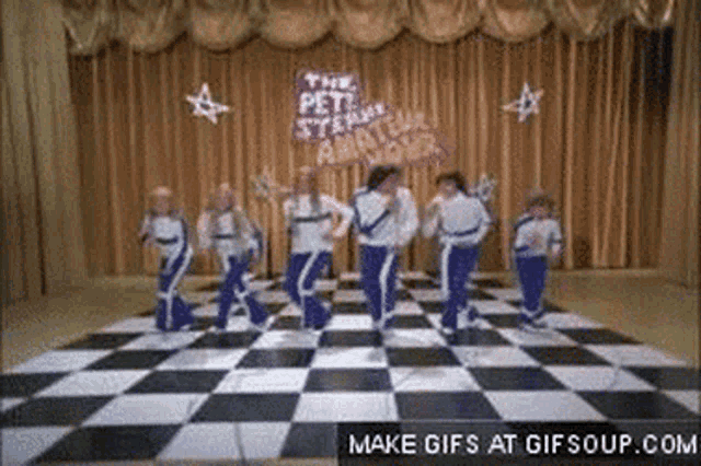 a group of children are dancing on a checkered floor in front of a sign that says " the pet stewardess "