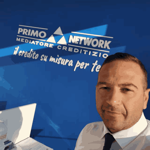 a man is standing in front of a blue wall that says primo network