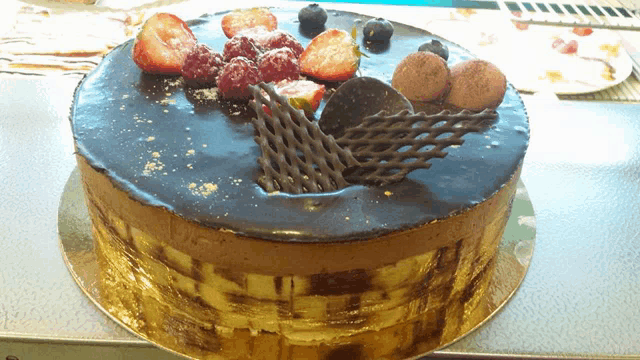 a chocolate cake with strawberries and blueberries on top on a table