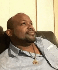 a man with a beard is sitting on a couch looking up .