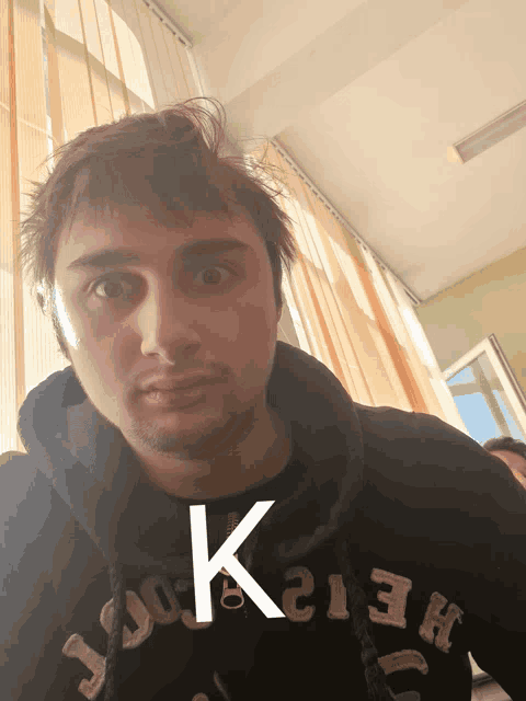 a man wearing a black hoodie with the letter k on the front