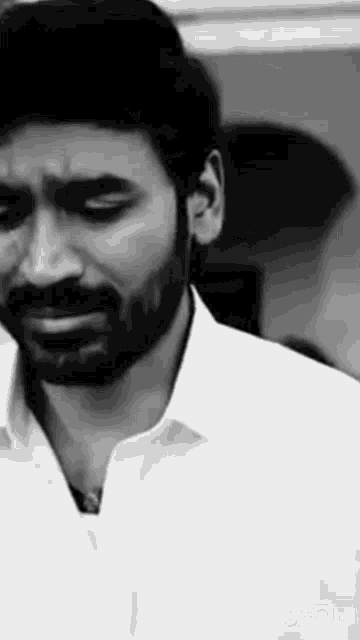 a black and white photo of a man with a beard crying with his eyes closed .