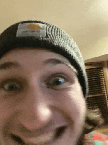 a close up of a man wearing a beanie and making a face .