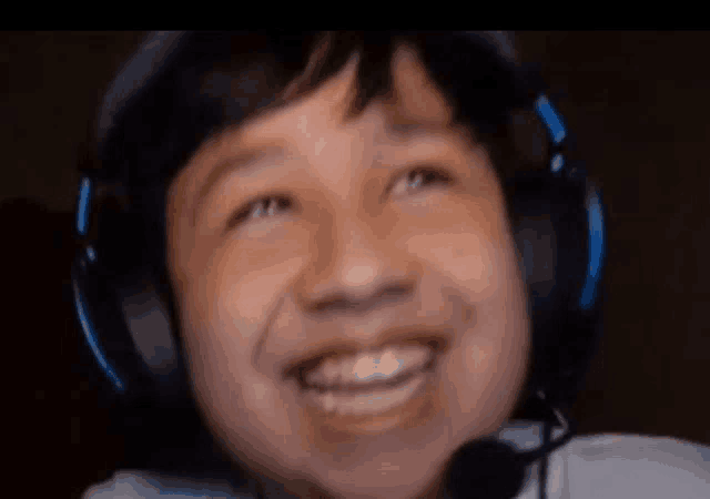 a young boy wearing headphones is smiling and looking up .