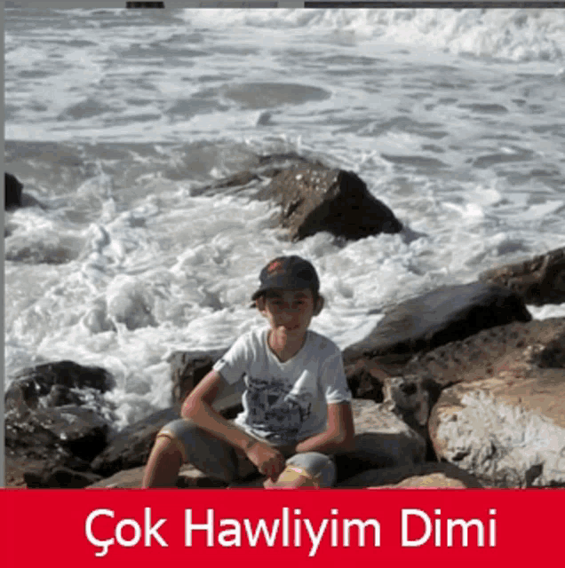 a boy is sitting on a rock near the ocean with the caption çok hawliyim dimi