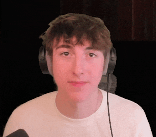 a young man wearing headphones looks at the camera with a black background