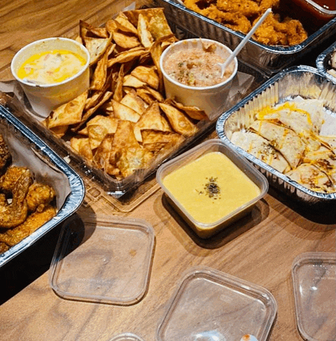 a table topped with a variety of food including a tray of chips