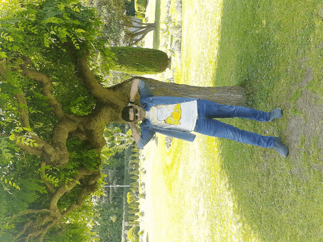 a man wearing a shirt that says bart simpson is standing under a tree