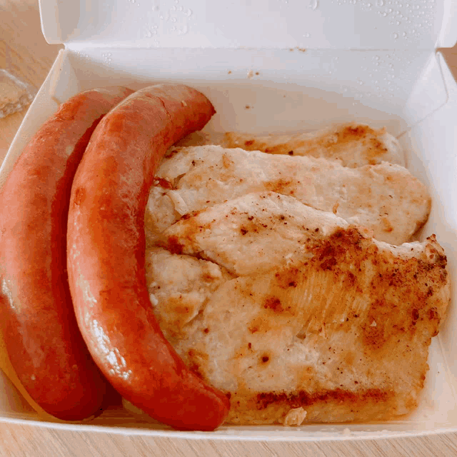 two sausages and a piece of chicken are in a box