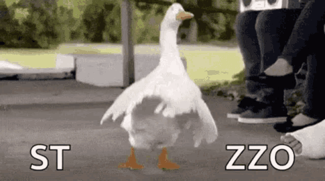 a white goose is standing on its hind legs in front of a group of people sitting on a bench .