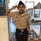 a young man in a military uniform salutes in front of a picture of a man in a military uniform .