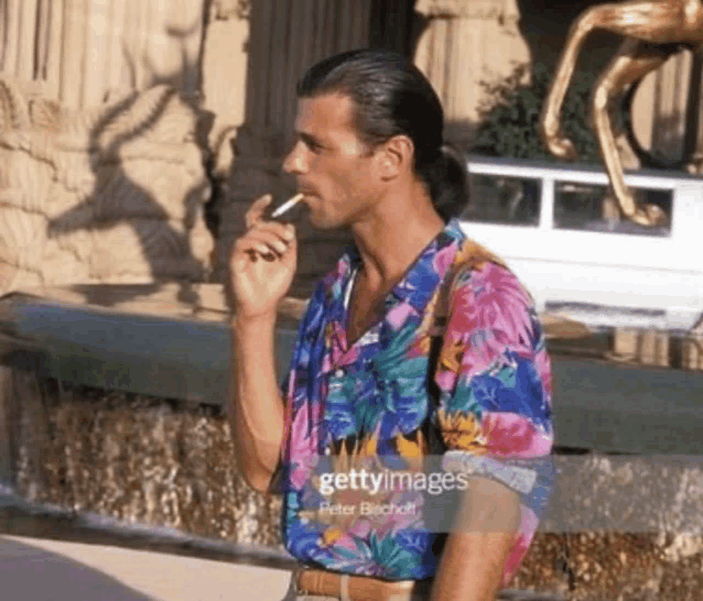 a man wearing a colorful shirt smoking a cigarette