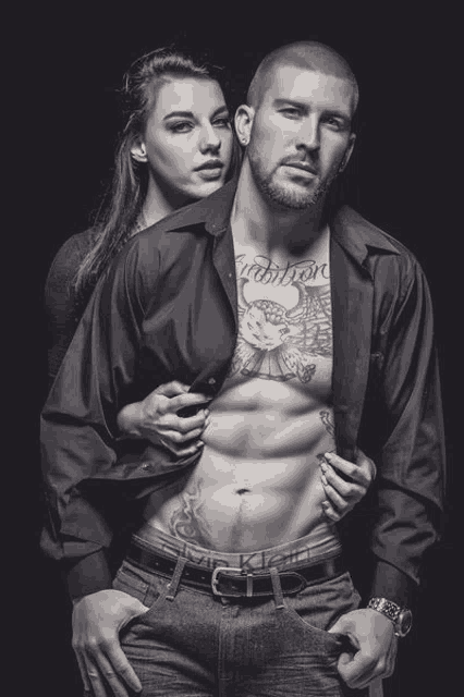 a man with a tattoo on his chest is being held by a woman in a black and white photo