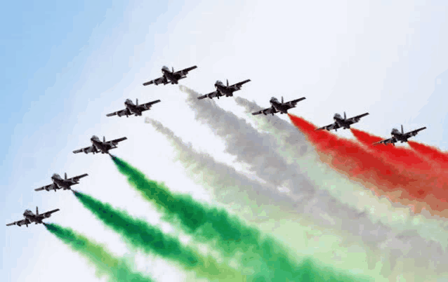 a group of fighter jets flying in formation with red white and green smoke coming out of their engines