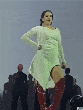 a woman in a white dress and red boots stands on a stage