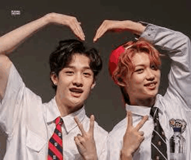 a couple of young men are making a heart shape with their hands .