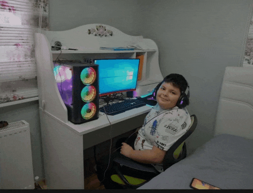 a young boy wearing headphones sits in front of a computer monitor