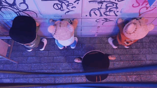 a group of stuffed animals are standing in front of a wall with graffiti on it