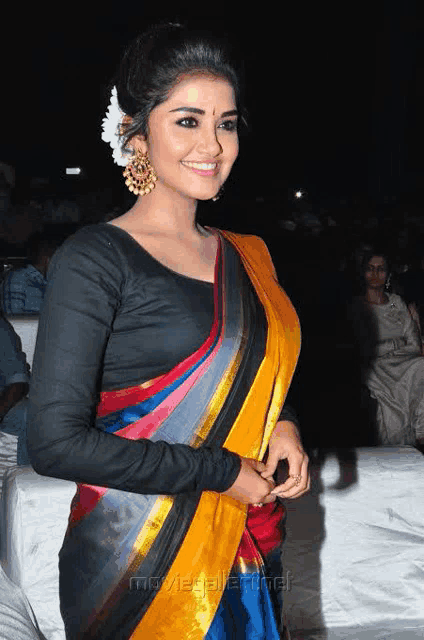 a woman with a flower in her hair is wearing a colorful striped saree