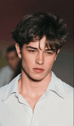 a close up of a young man 's face with a white shirt