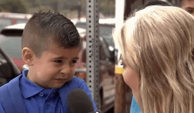 a little boy is crying while being interviewed by a woman in a parking lot .