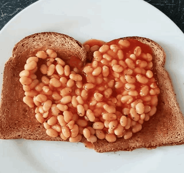 two slices of toast with baked beans on them on a white plate