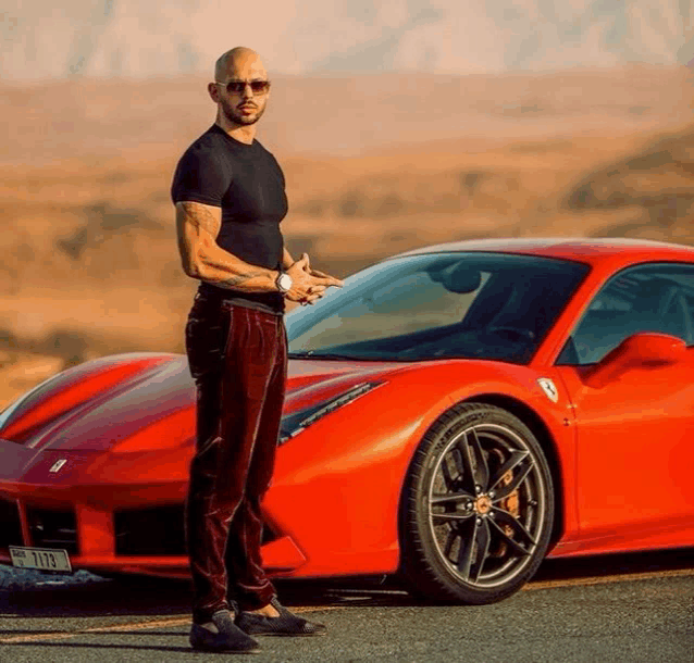 a man is standing in front of a red sports car with a license plate that says yts