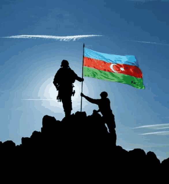 two soldiers holding a flag on top of a rocky hill