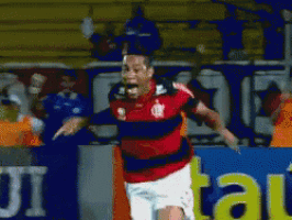 a man in a red and black striped shirt is running on a soccer field in front of a sign that says ui