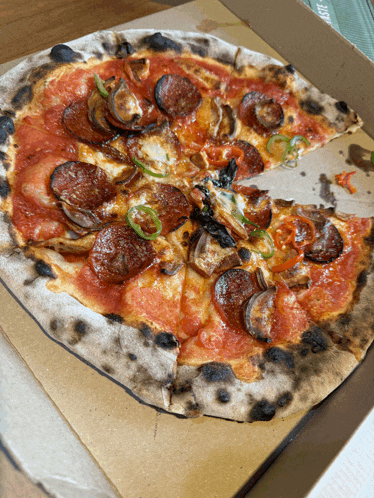 a pizza in a cardboard box with a slice missing