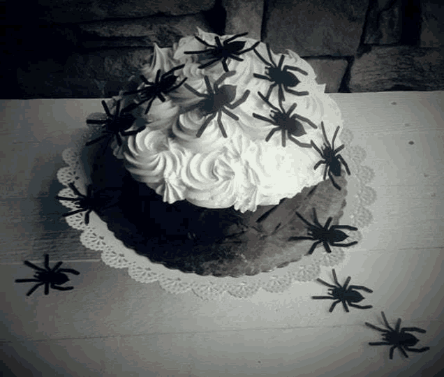 a black and white photo of a cake with spiders on top