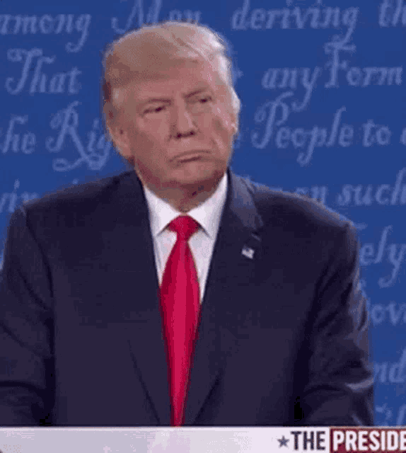 donald trump is making a funny face while giving a speech at a debate .