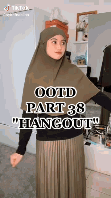 a woman wearing a hijab is standing in front of a mirror with the words " ootd part 38 hangout "